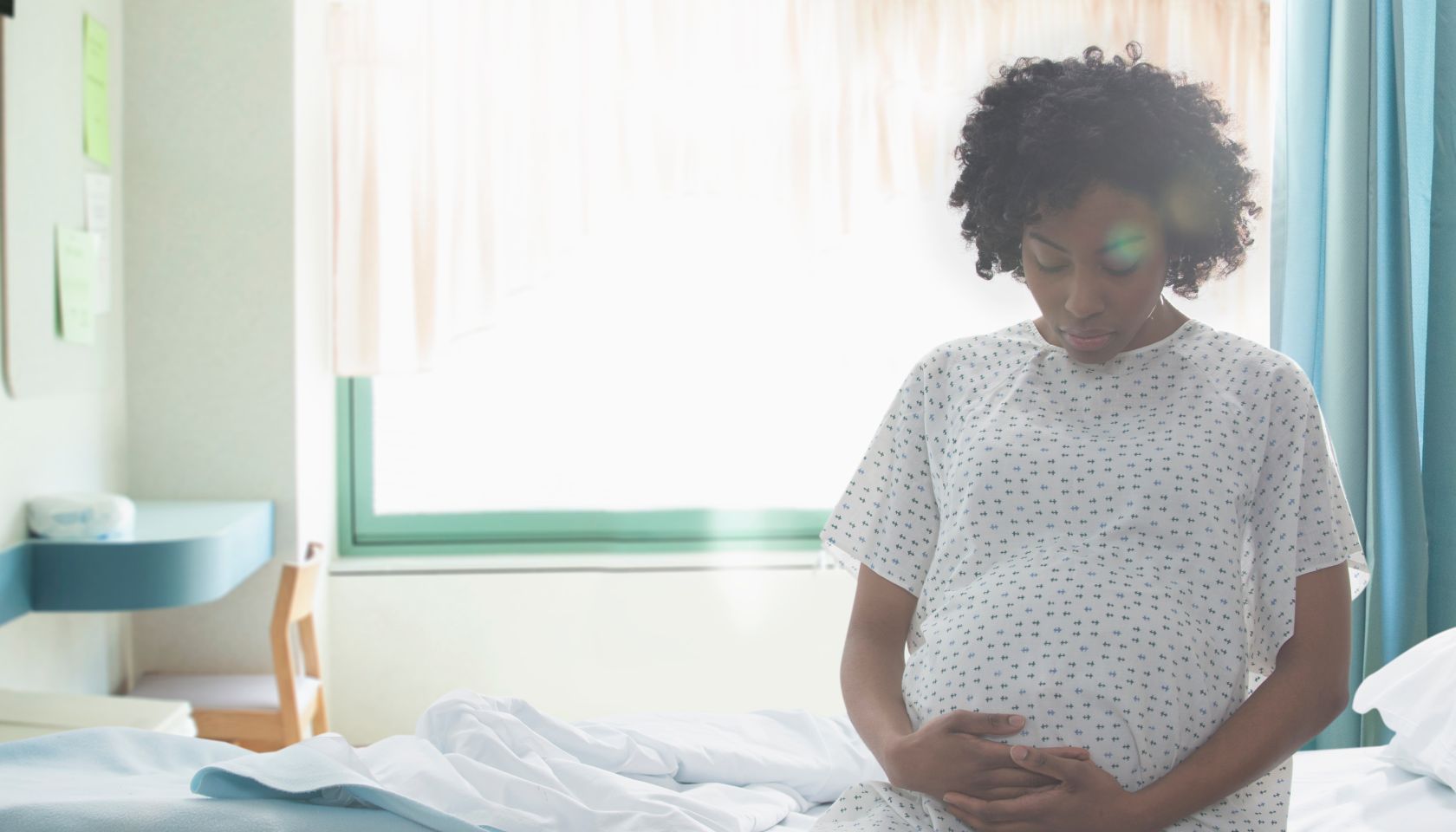 Pregnant African American woman holding her stomach in hospital