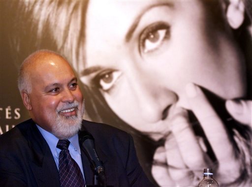 FILE - In this Sept. 8, 1999 file photo, Rene Angelil responds to a question with a giant photograph of his wife singer Celine Dion in the background during a news conference in Montreal. Angelil, Celine Dion's husband and manager, has died at his suburban Las Vegas home, authorities said Thursday, Jan. 14, 2016. He was 73 and had battled throat cancer. (Paul Chiasson/The Canadian Press via AP, File)