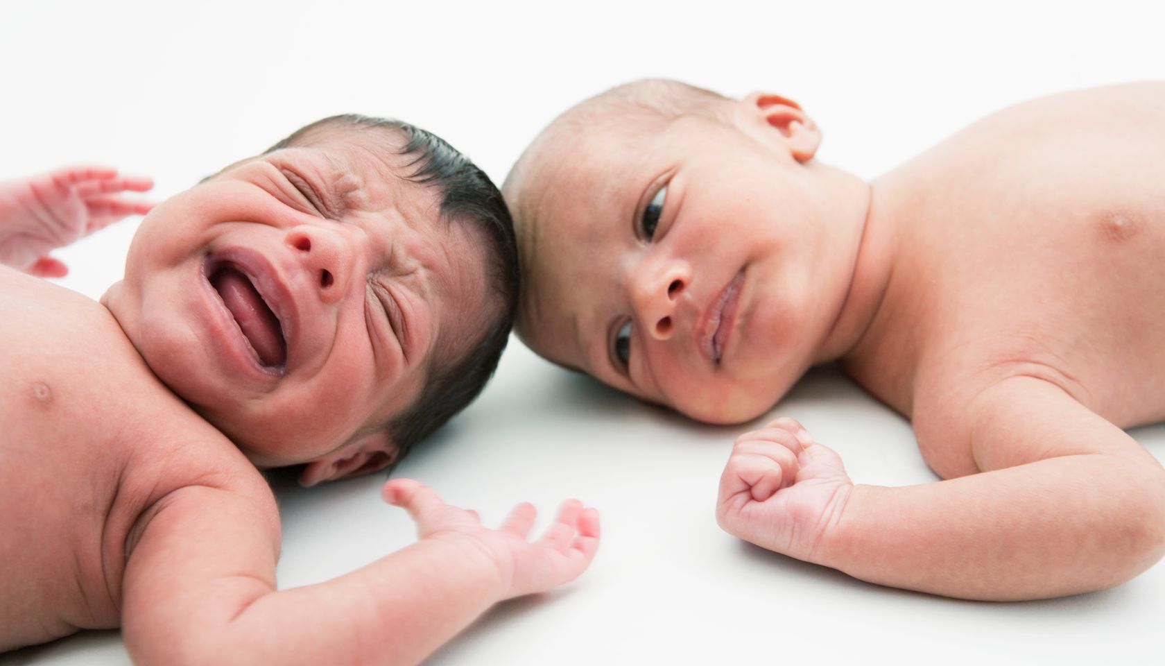 2 young babies lying down, 1 crying
