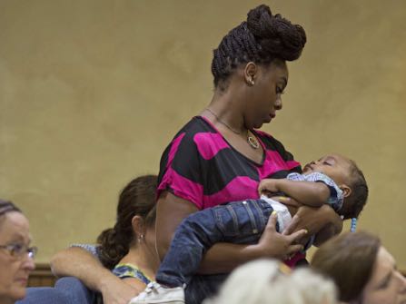 Naomi Clark, 27, holds her sleeping son, 1-year-old Caylei Clark, during services at South Walker Baptist Church in Walker, La., Sunday, Aug. 21, 2016. Clark said she moved to Walker two years ago with her husband who is a truck driver. Her and her two children were with her husband in the truck when the flood struck Walker last week. (AP Photo/Max Becherer)
