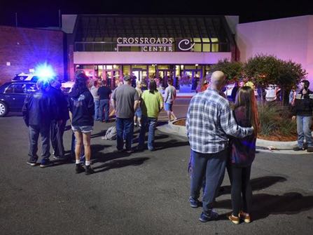 People stand near the entrance on the north side of Crossroads Center mall between Macy's and Target as officials investigate a reported multiple stabbing incident, Saturday, Sept. 17, 2016, in St. Cloud, Minn. Police said multiple people were injured at the St. Cloud shopping mall on Saturday evening in an attack possibly involving both shooting and stabbing. The suspect is believed to be dead, St. Cloud Police Sgt. Jason Burke told the St. Cloud Times. (Dave Schwarz/St. Cloud Times via AP)