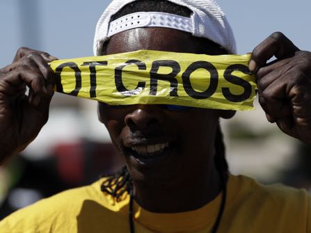 A man covers his eyes with police tape during a protest, Wednesday, Sept. 28, 2016, in El Cajon, Calif. Dozens of demonstrators on Wednesday protested the killing of a black man shot by an officer after authorities said the man pulled an object from a pocket, pointed it and assumed a "shooting stance." (AP Photo/Gregory Bull)