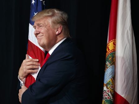 Republican presidential candidate Donald Trump hugs a flag as he arrives to speak to a campaign rally, Monday, Oct. 24, 2016, in Tampa, Fla. (AP Photo/ Evan Vucci)