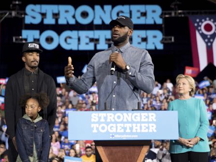 LeBron James, center, accompanied by Cleveland Cavaliers basketball player J. R. Smith, left, his daughter Demi, bottom left, and Democratic presidential candidate Hillary Clinton, right, speaks at a rally at the Cleveland Public Auditorium in Cleveland, Sunday, Nov. 6, 2016. (AP Photo/Andrew Harnik)