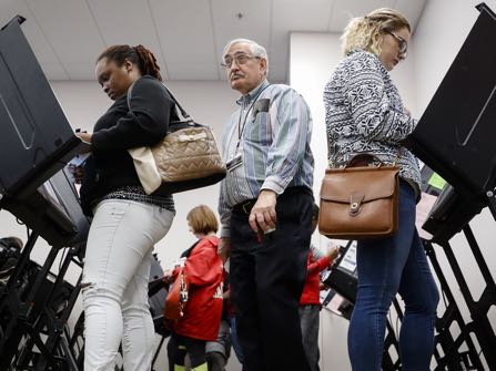 Polling worker Greg Caplinger, of Columbus, Ohio, center, passes between early voters at the Franklin County Board of Elections, Monday, Nov. 7, 2016, in Columbus, Ohio. Heavy turnout has caused long lines as voters take advantage of their last opportunity to vote before election day. (AP Photo/John Minchillo)