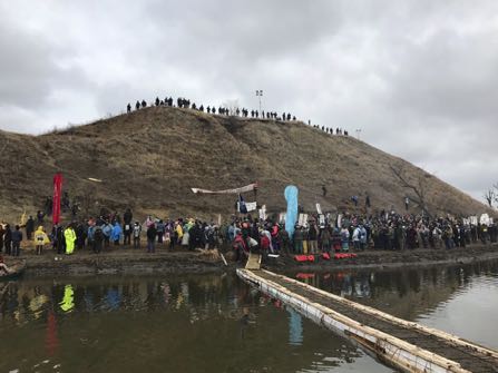 In this photo provided by Nancy Trevino, protesters against the Dakota Access oil pipeline gather at and around a hill, referred to as Turtle Island, where demonstrators claim burial sites are located, Thursday, Nov. 24, 2016 in Cannon Ball, N.D. The hill is across a body of water from where hundreds and times thousands of people have camped out for months to protest the construction of the four-state pipeline. (Nancy Trevino via AP)