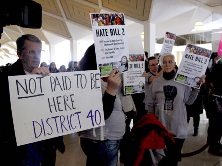 Opponents of HB2 hold signs outside the N.C. House chambers gallery as the N.C. General Assembly convenes for a special session at the Legislative Building in Raleigh, NC on Dec. 21, 2016.