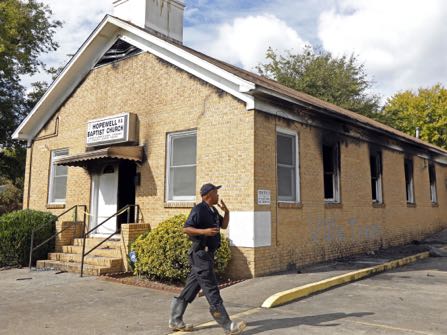 FILE-In this Wednesday, Nov. 2, 2016 file photoA state fire marshal investigates the fire damaged Hopewell M.B. Baptist Church in Greenville, Miss., Wednesday, Nov. 2, 2016. "Vote Trump" was spray-painted on an outside wall of the black member church. Fire Chief Ruben Brown tells The Associated Press that firefighters found flames and smoke pouring from the sanctuary of the church just after 9 p.m. Tuesday. (AP Photo/Rogelio V. Solis, File)