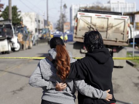 Two women watch the scene of a warehouse fire Sunday, Dec. 4, 2016, in Oakland, Calif. (AP Photo/Marcio Jose Sanchez)