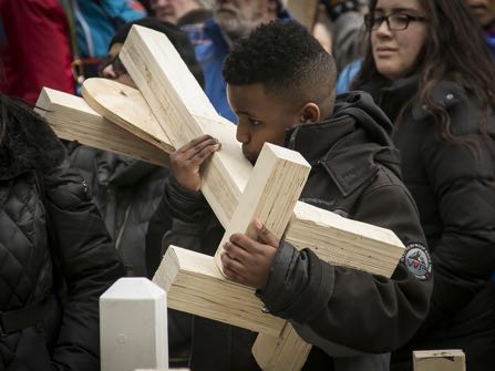 Colin Clark, 12, kisses the cross for his father, 55-year-old Lazane Clark, who was shot to death in February, during a march along Michigan Avenue, Saturday, Dec. 31, 2016, in Chicago. Hundreds of people carried crosses Saturday for each person slain in Chicago this year during the march. (Ashlee Rezin/Chicago Sun-Times via AP)