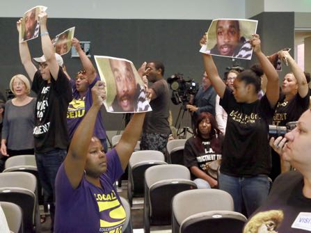 FILE - In this Aug. 11, 2015, file photo, protestors, holding photos of Ezell Ford, chant for Los Angeles Police Chief Charlie Beck’s firing during a Los Angeles Police Commission meeting in downtown Los Angeles. Two Los Angeles police officers acted in self-defense when they fatally shot a 25-year-old black man during a struggle over an officer's gun and will not face criminal charges for the 2014 shooting that led to protests, prosecutors said Tuesday, Jan. 24, 2017. (AP Photo/Nick Ut, File)