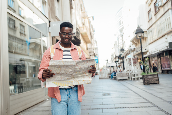 Portrait of a young man on a journey exploring the city map