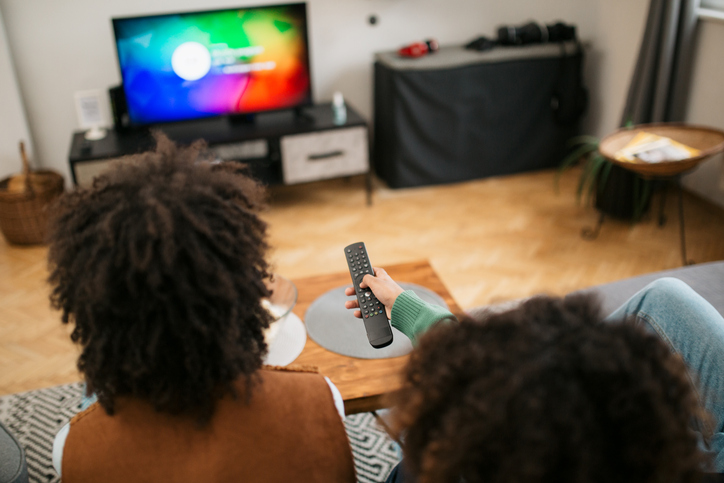 Rear view of a happy African American family watching TV together