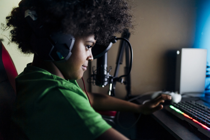 Young boy wearing headphones playing video game at home