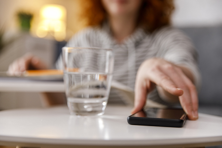 Reaching for her smart phone to check text messages