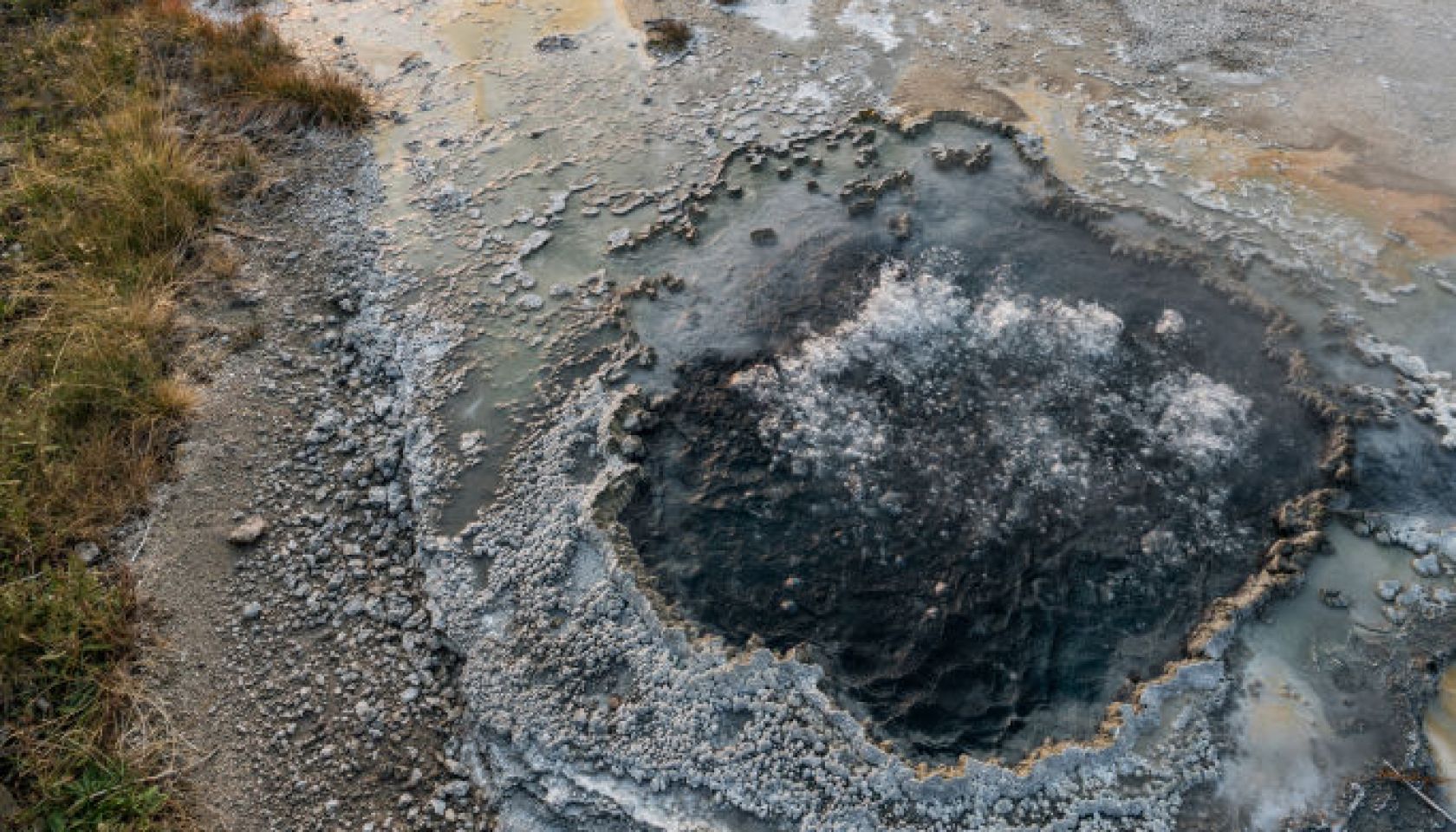 The East Chinaman Spring bubbles and steams by the Firehole River in the Upper Geyser Basin of Yellowstone National Park in Wyoming, USA.