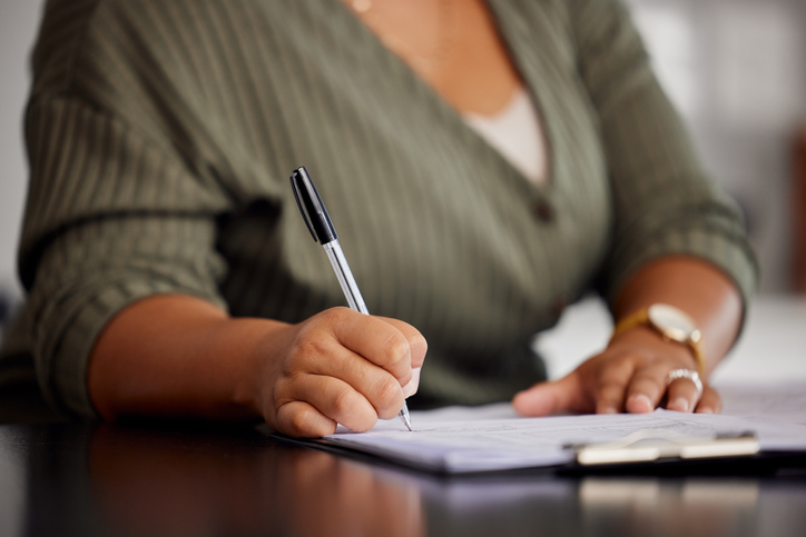 Unrecognizable shot of a woman doing some paperwork at home
