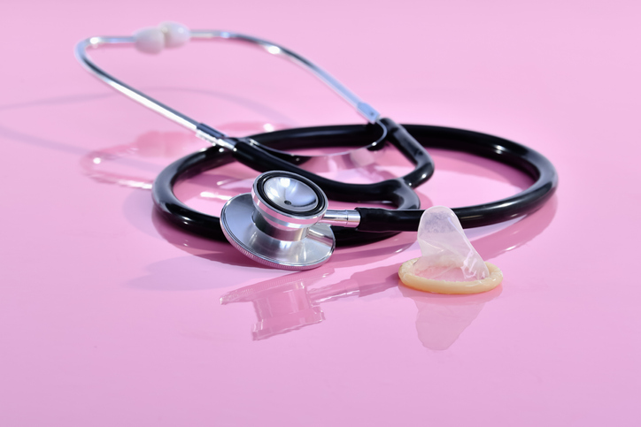 Close-Up Of Condom And Stethoscope Against Pink Background