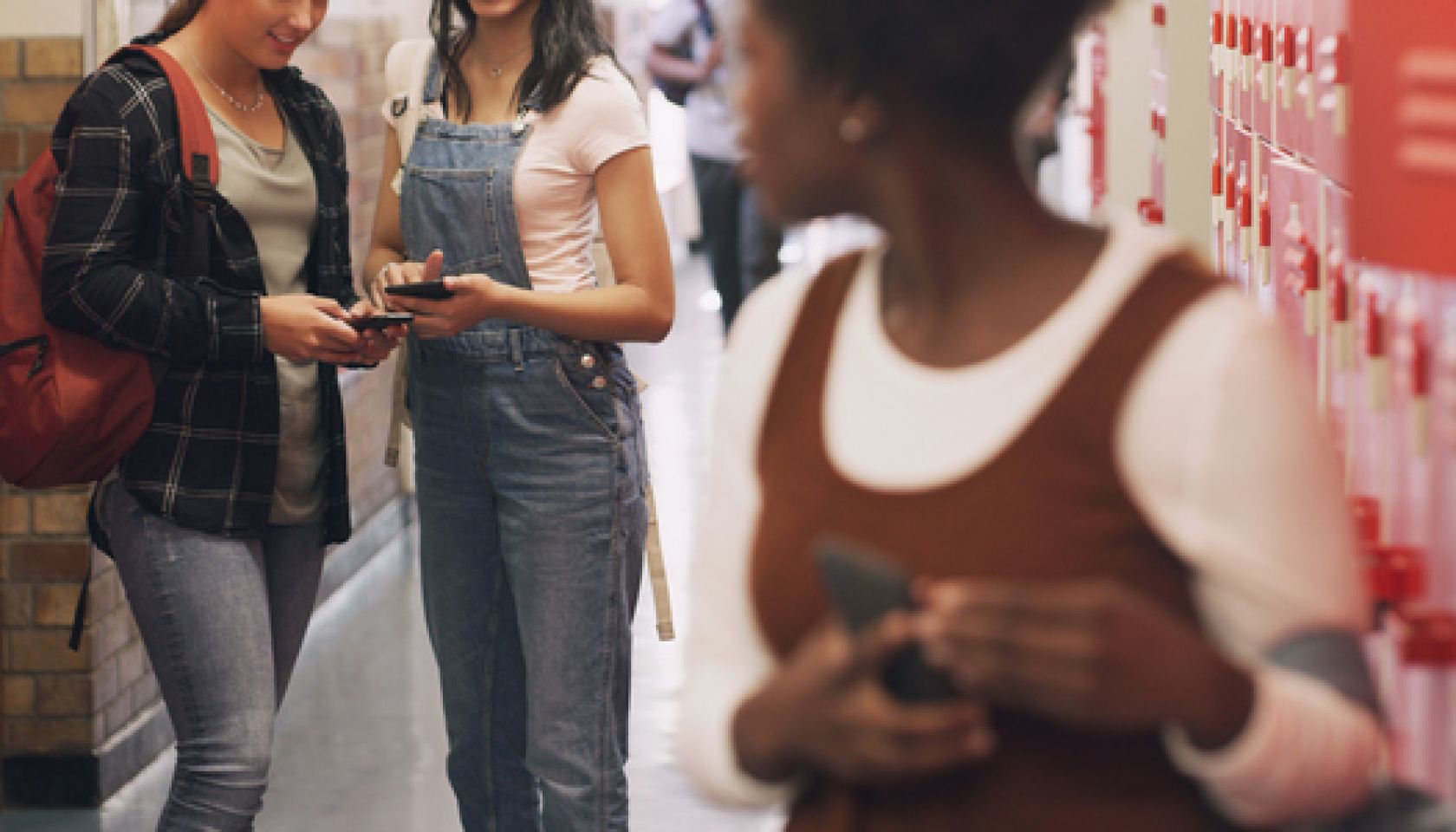 Shot of a teenage girl using a smartphone next to her locker and being bullied at high school
