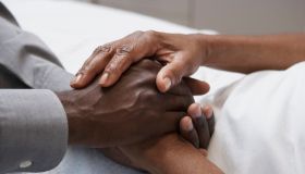 Close up of African man holding hands in hospital