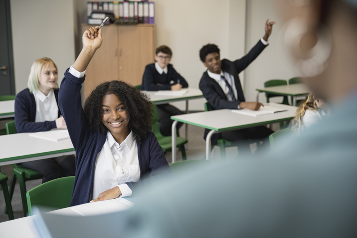 Smiling teenagers participating in classroom discussion