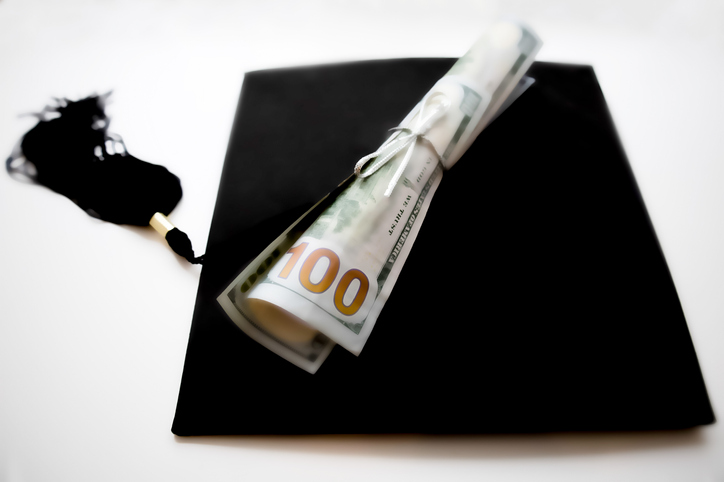 school diploma wrapped in $100 bills & traditional black graduation cap with tassel