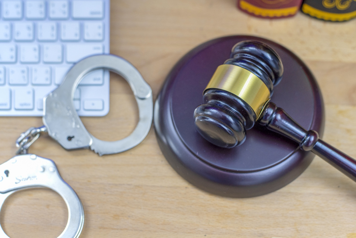Laptop, wooden gavel and handcuffs on light table, closeup. Cyber crime
