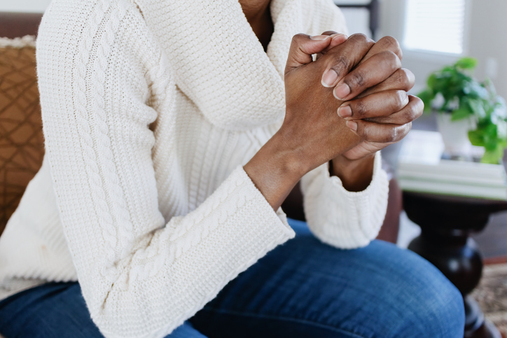 Woman Sits in Chair With Hands Clasped