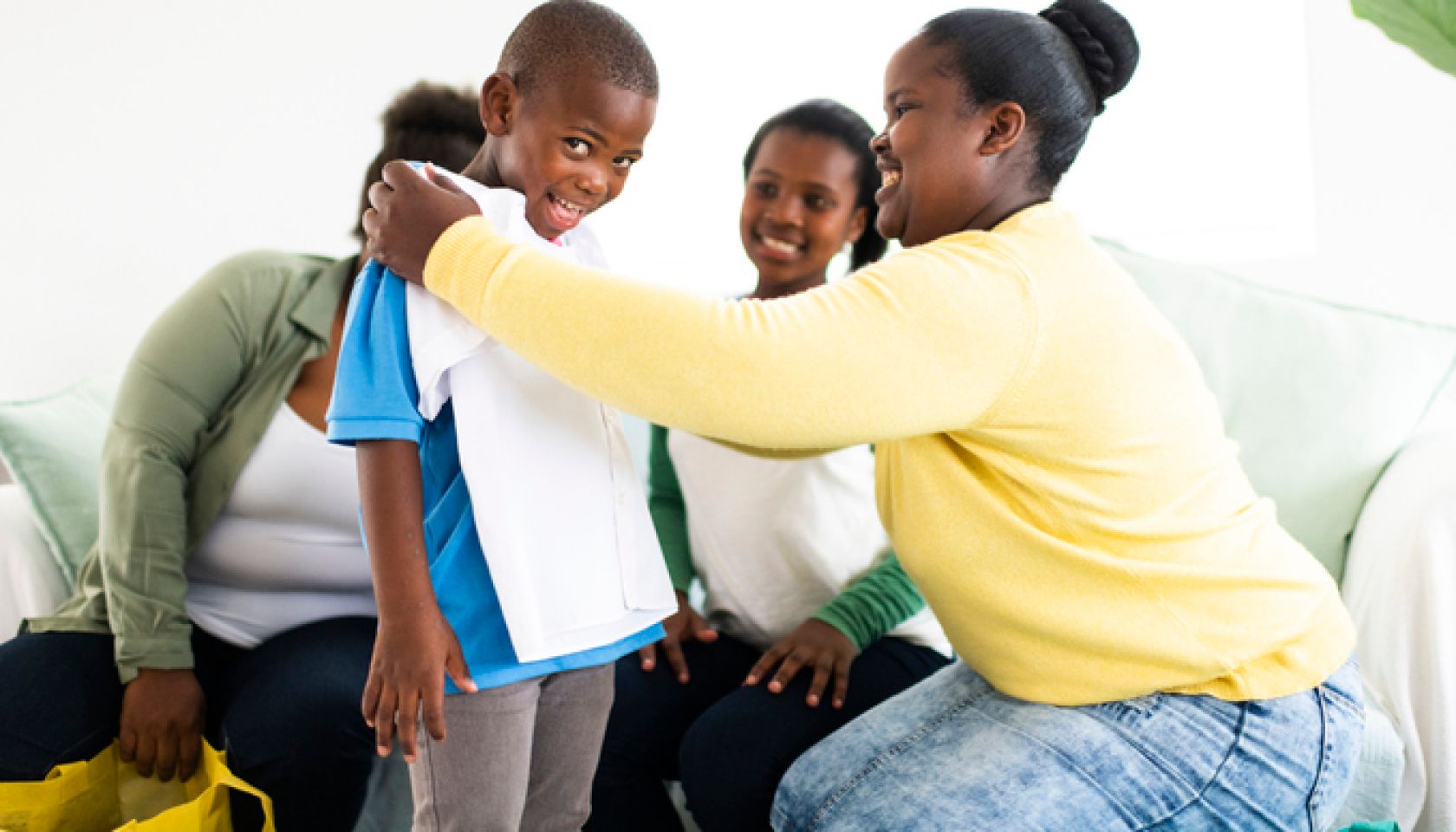 Mother holds new school shirt against excited boys chest