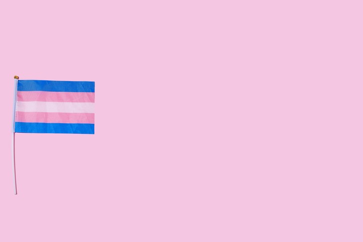 Transgender lgbt community flag, on the left side, on pink background. Gay pride day, transgender, transsexual and binary person concept.