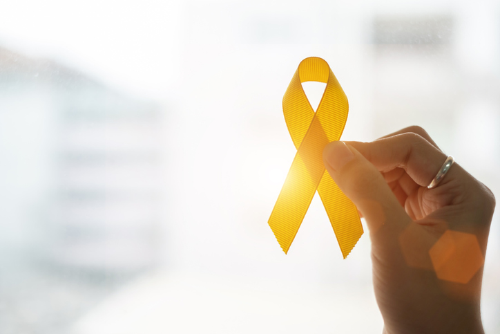 Suicide prevention and Childhood Cancer Awareness, Yellow Ribbon on wooden background for supporting people living and illness. children Healthcare and World cancer day concept