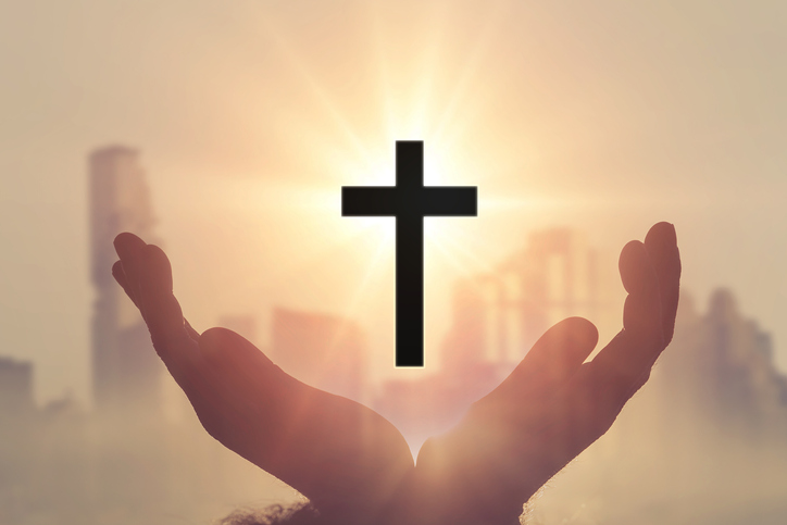Silhouette of cross in hand in faith to god and redemption concept