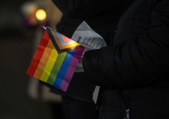 A woman holds a Pride flag during the vigil...