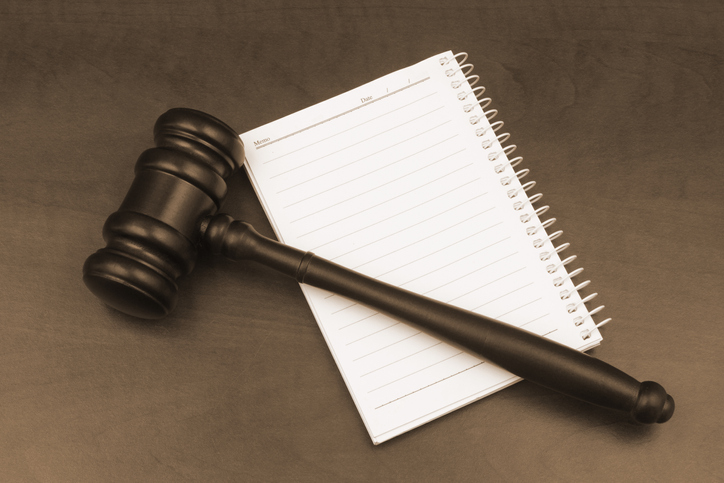 Blank note pad with pen and judge gavel on wooden table.