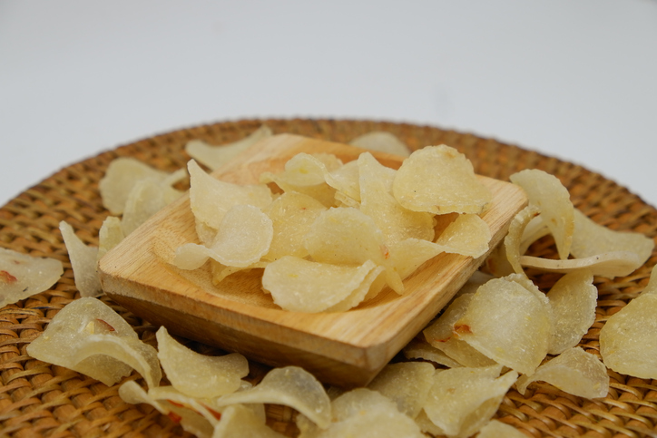 Raw crackers Unyil (Unyil chips), traditional cassava chips from Indonesia, served on rattan tray, side view