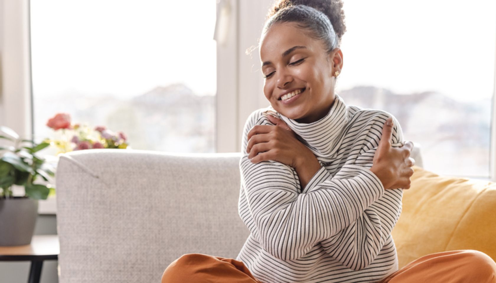 Smiling beautiful woman hugging self