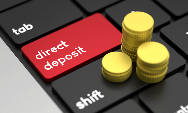 Close-Up Laptop Keyboard With Direct Deposit Button and Gold Coins