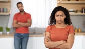 Offended sad unhappy millennial black woman in red t-shirt ignores husband after quarrel in kitchen interior