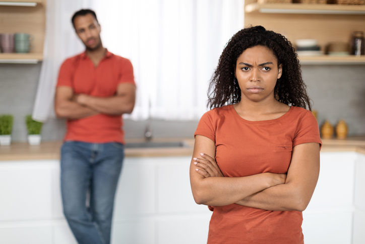 Offended sad unhappy millennial black woman in red t-shirt ignores husband after quarrel in kitchen interior