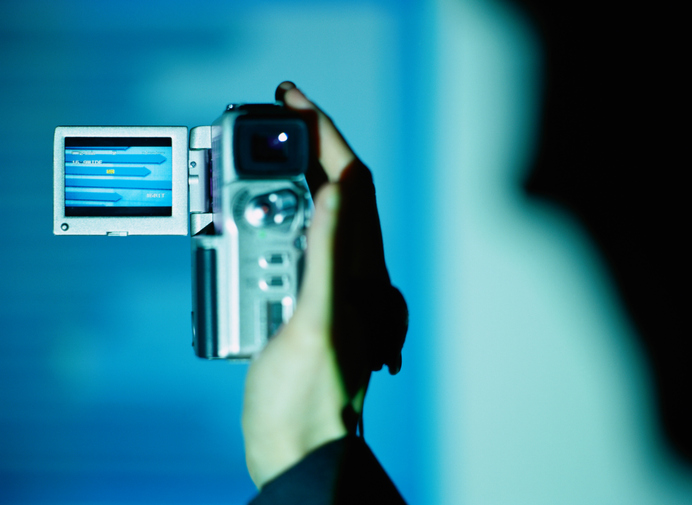 Person holding digital video camera, close-up (blue tone)