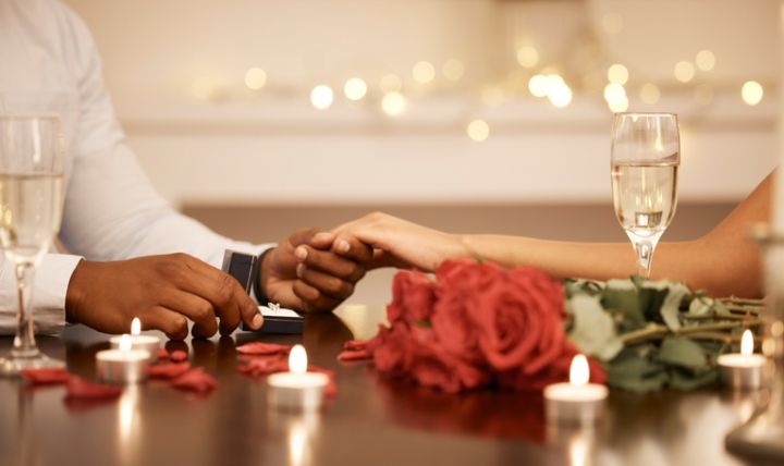 Love, engagement and couple holding hands with wedding ring at restaurant table for proposal, date and celebration. Romance, champagne and happiness with diamond jewellery for marriage