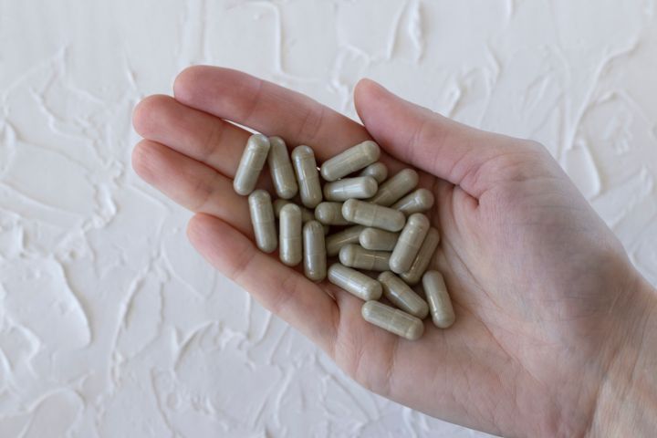 Gray herbal capsules in a woman's hand in close-up