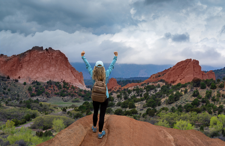 Woman hiker with hands up on top of the mountain.