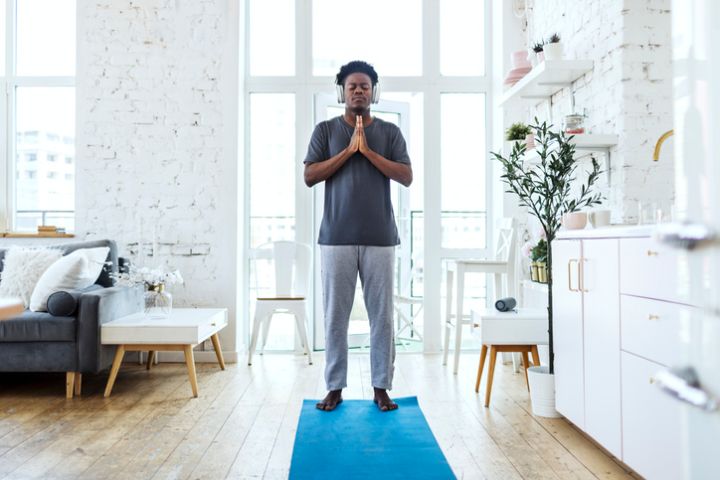 Young adult black man practicing yoga at home