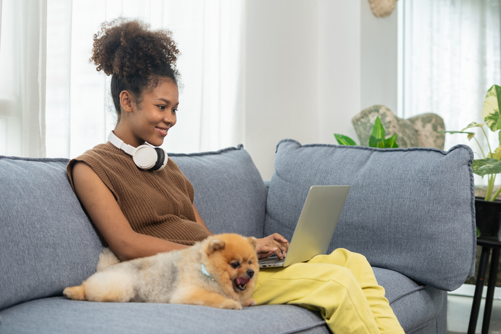 Young women working in the living room with her dog