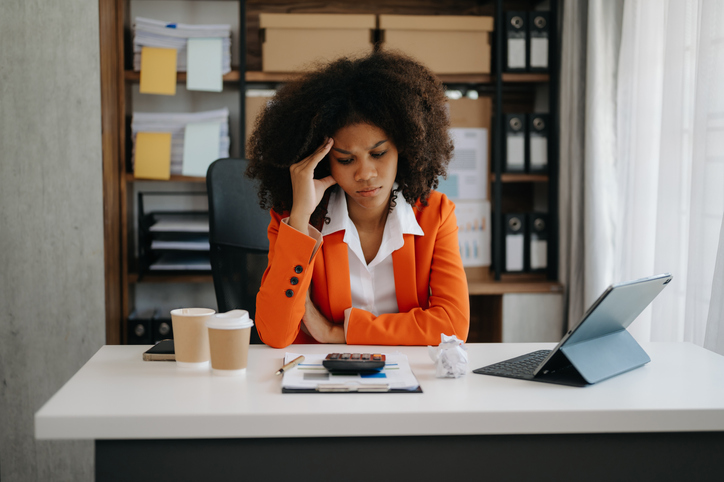 African business woman is stressed, bored, and overthinking from working on a tablet at the office.