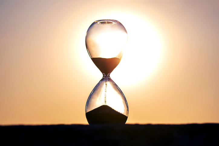 Hourglass counts the length of time against the background of the evening sun. The concept of the fluidity of life time in the universe. time and light