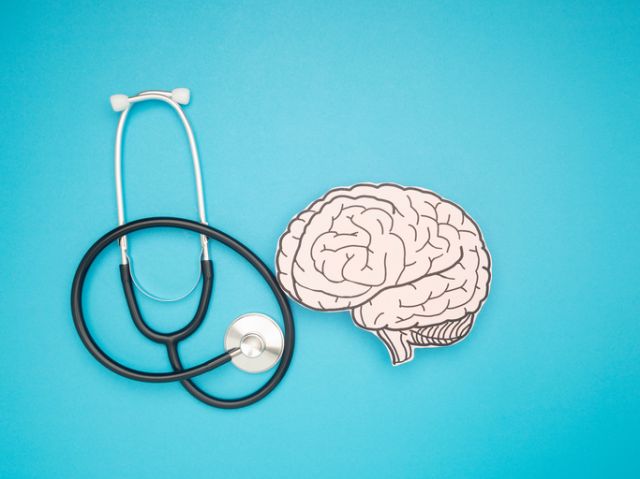 A stethoscope and brain shape made from paper over a blue background