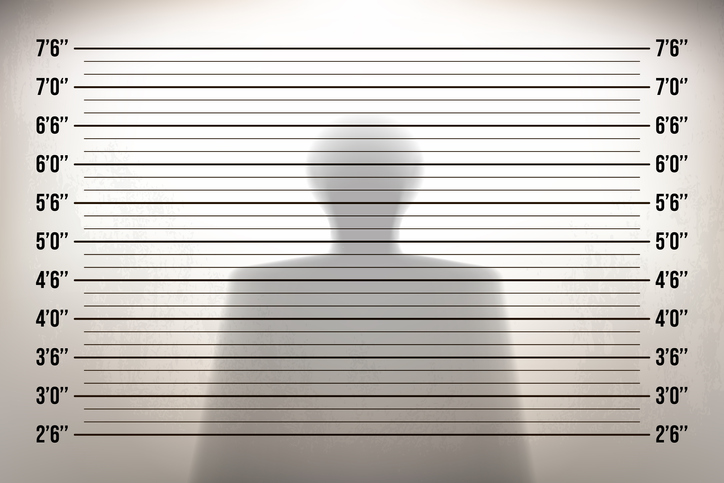 Mugshot in a police station with a shadow of man