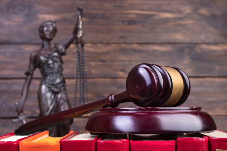 Law concept - Open law book, Judge's gavel, scales, Themis statue on table in a courtroom or law enforcement office.